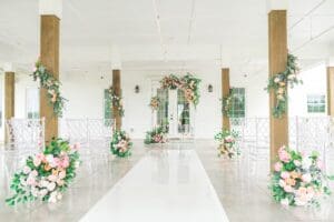 A white aisle way with flowers and greenery.