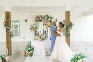 A couple is dancing in front of a floral arch.