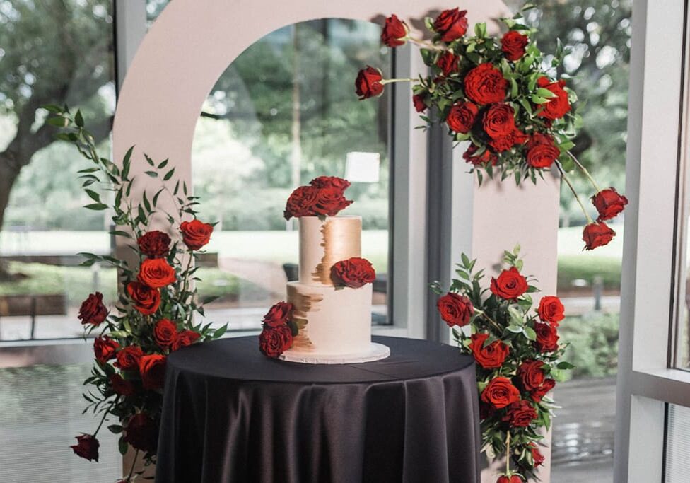 A table with two cakes on it and red roses