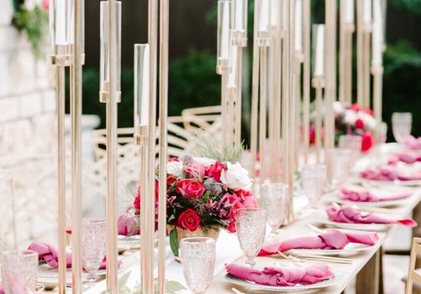 A long table with pink napkins and candles on it